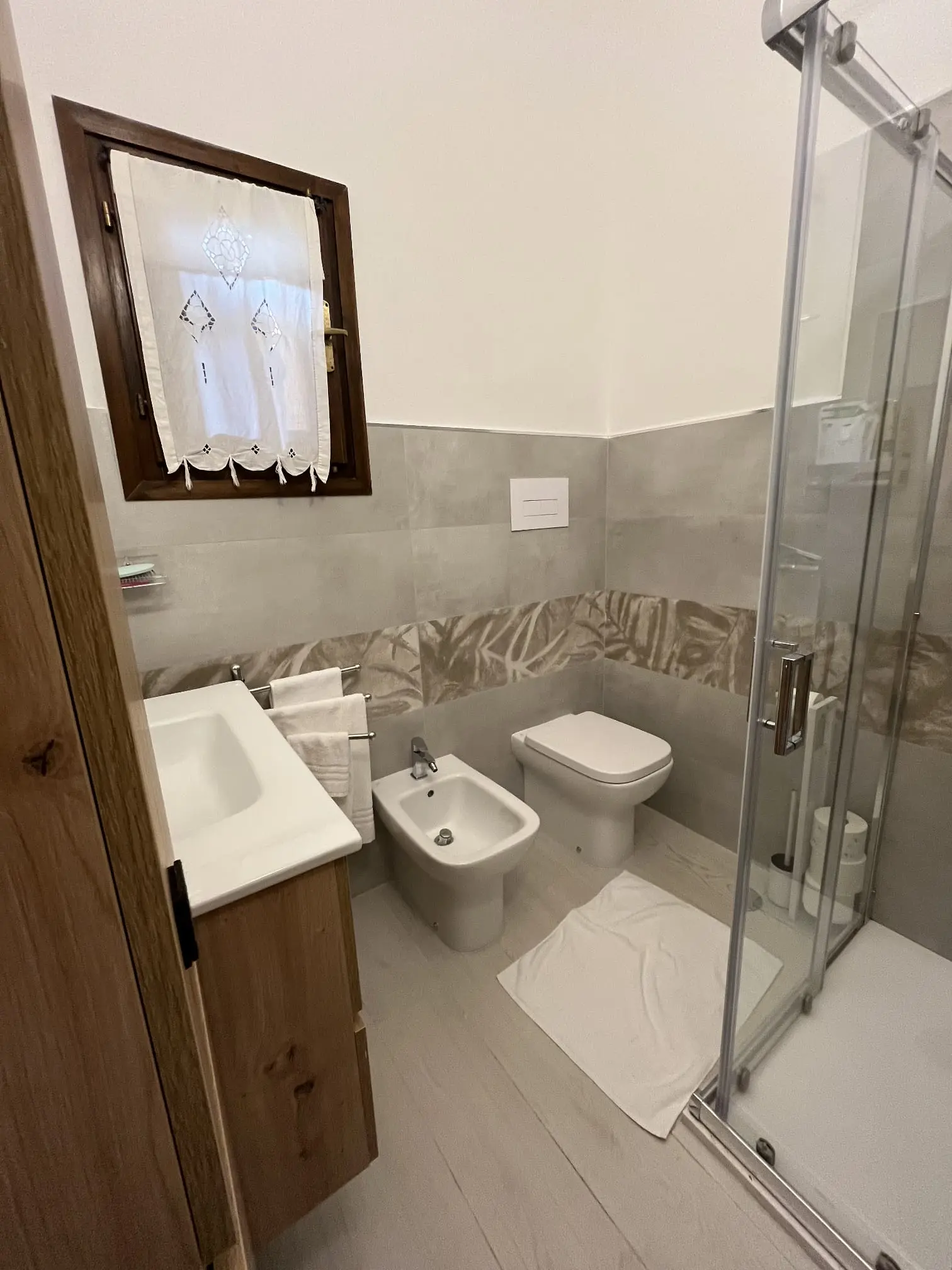 Indoor bathroom with shower, bidet, toilet and curtained window