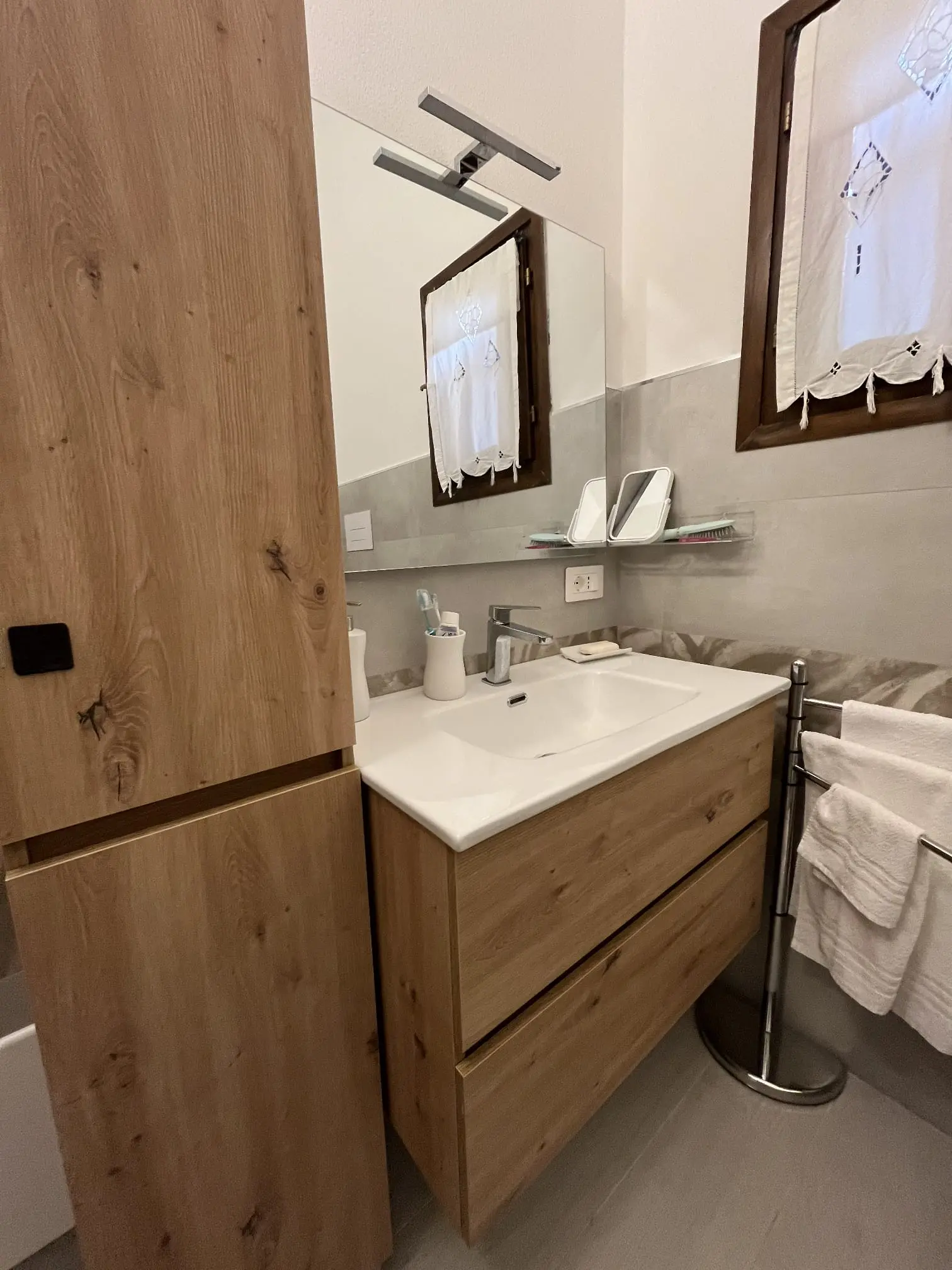 Wood vanity, washbasin, mirror and fresh towels in the villa bathroom