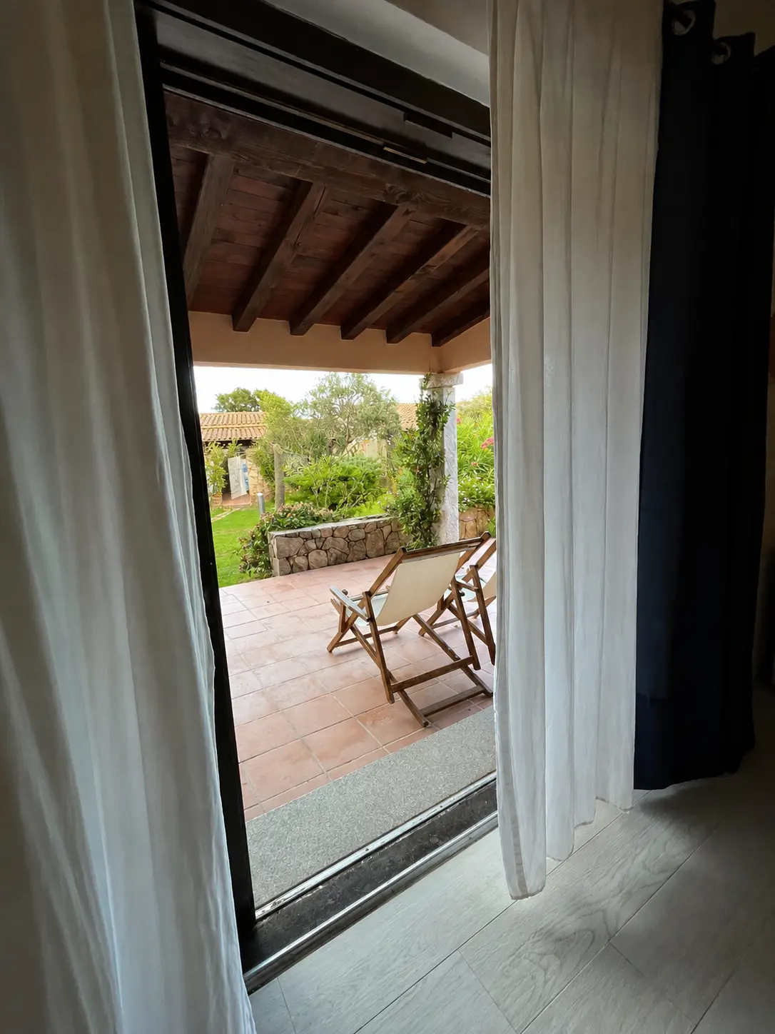 Bedroom doorway opening to the covered terrace and garden deckchairs