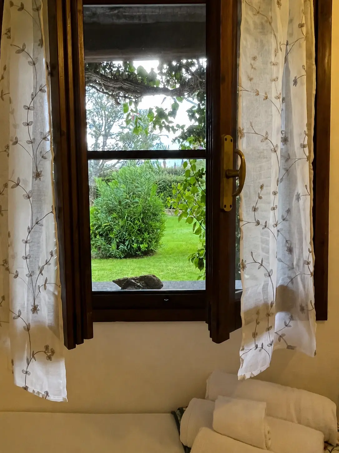 Mediterranean garden seen through a bedroom window with fresh towels below