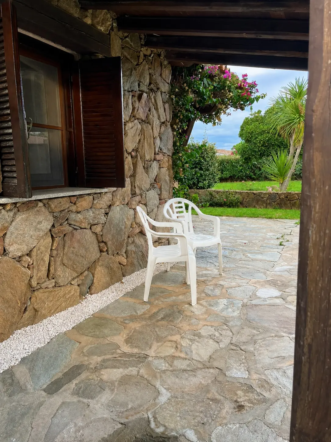 Covered veranda with traditional stone paving and Mediterranean garden