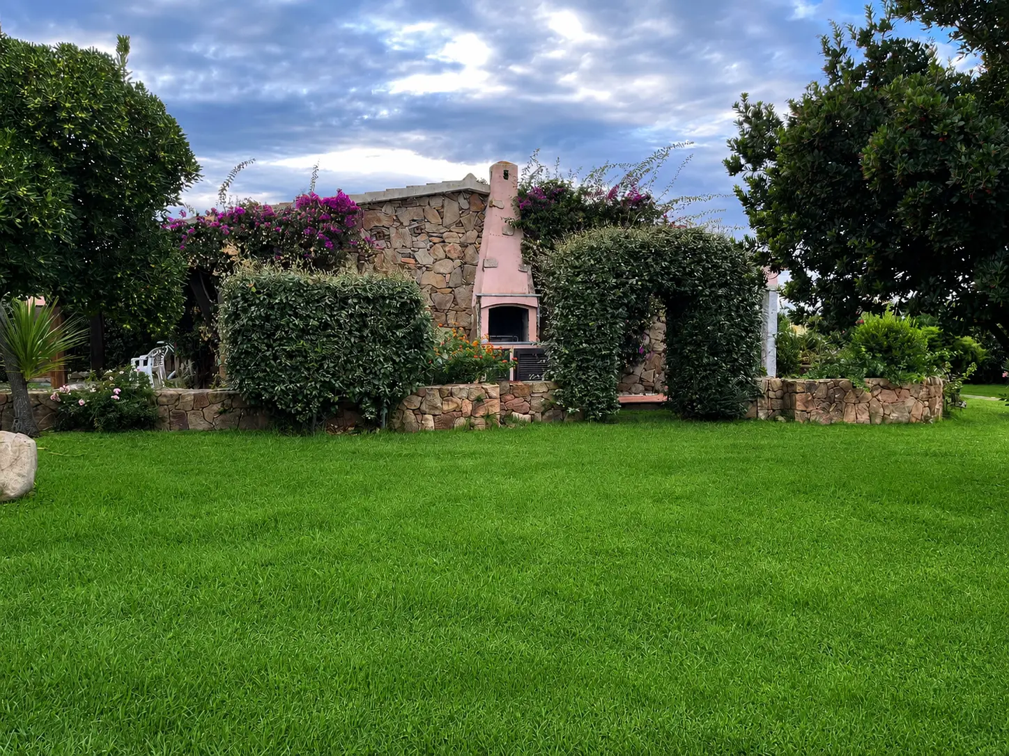 Private green lawn and built-in stone barbecue beside the villa
