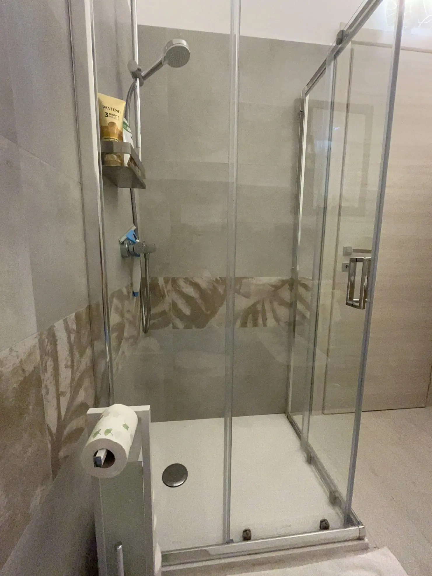 Glass shower enclosure and neutral stone-look tiles in the indoor bathroom