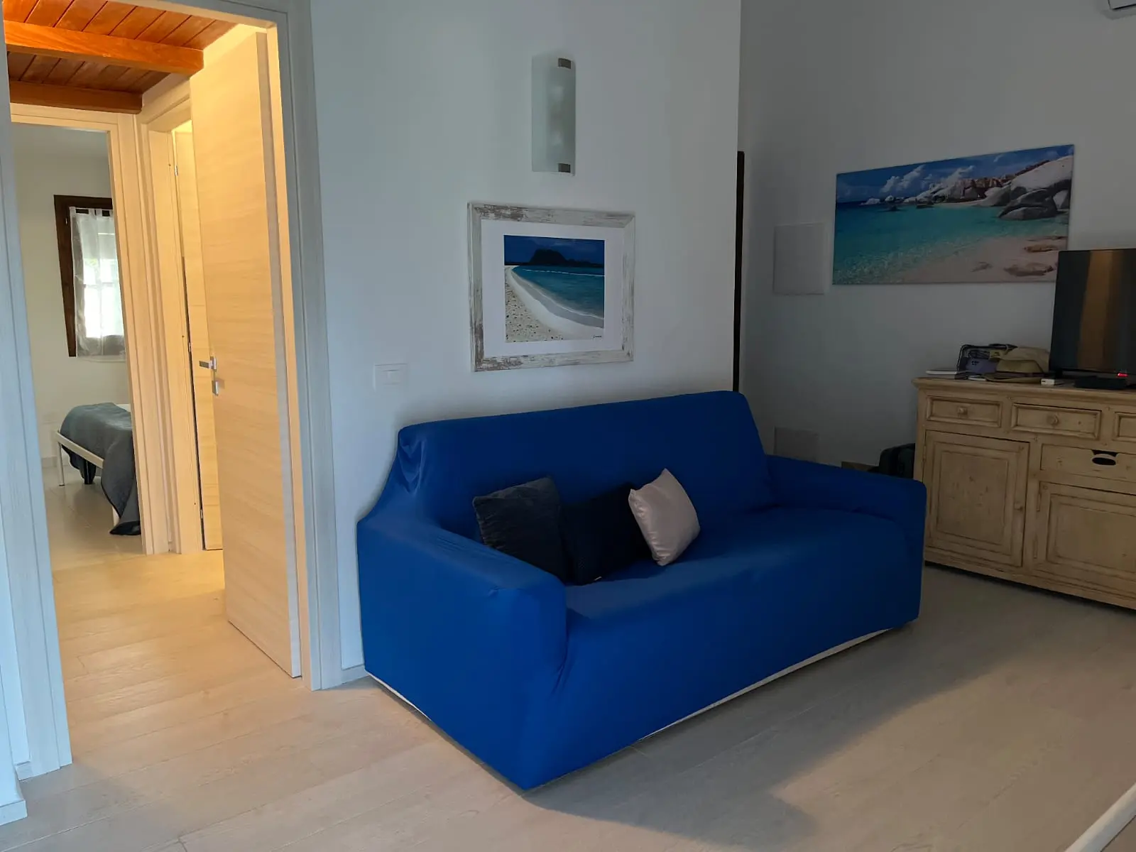 Living room with blue sofa and view toward the queen bedroom