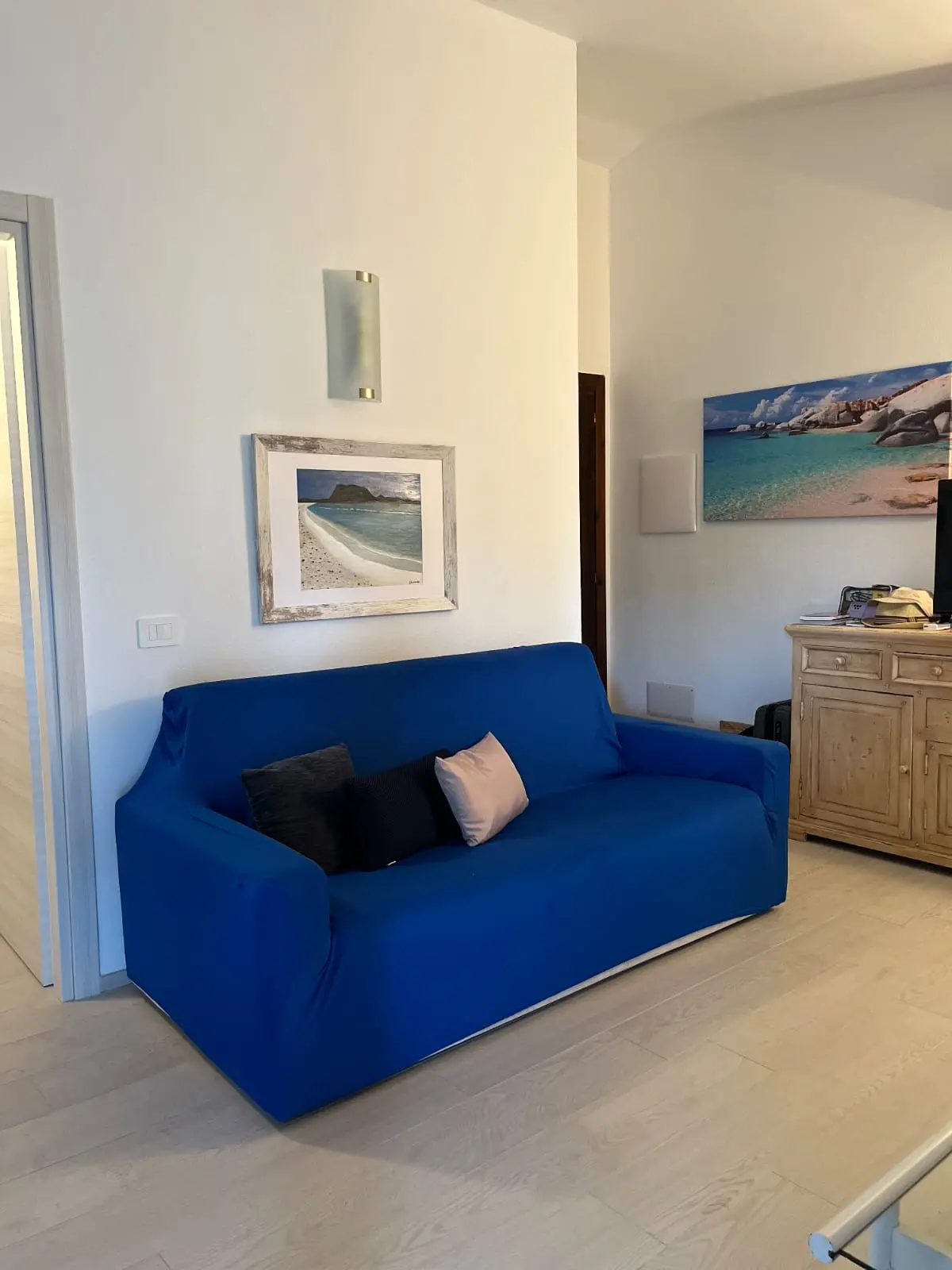 Comfortable blue lounge sofa beneath Sardinian coastal artwork