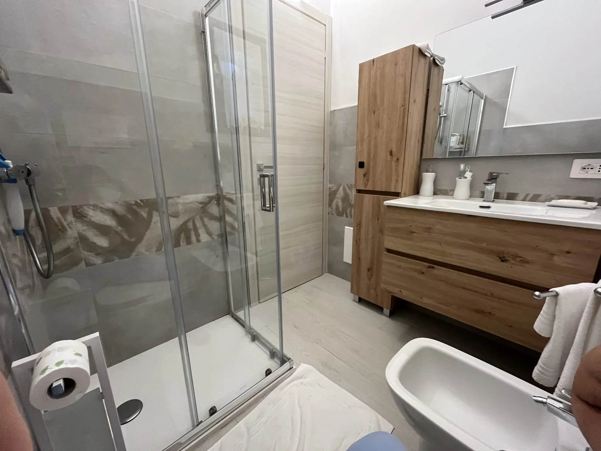 Wide view of the villa bathroom with glass shower and wood vanity