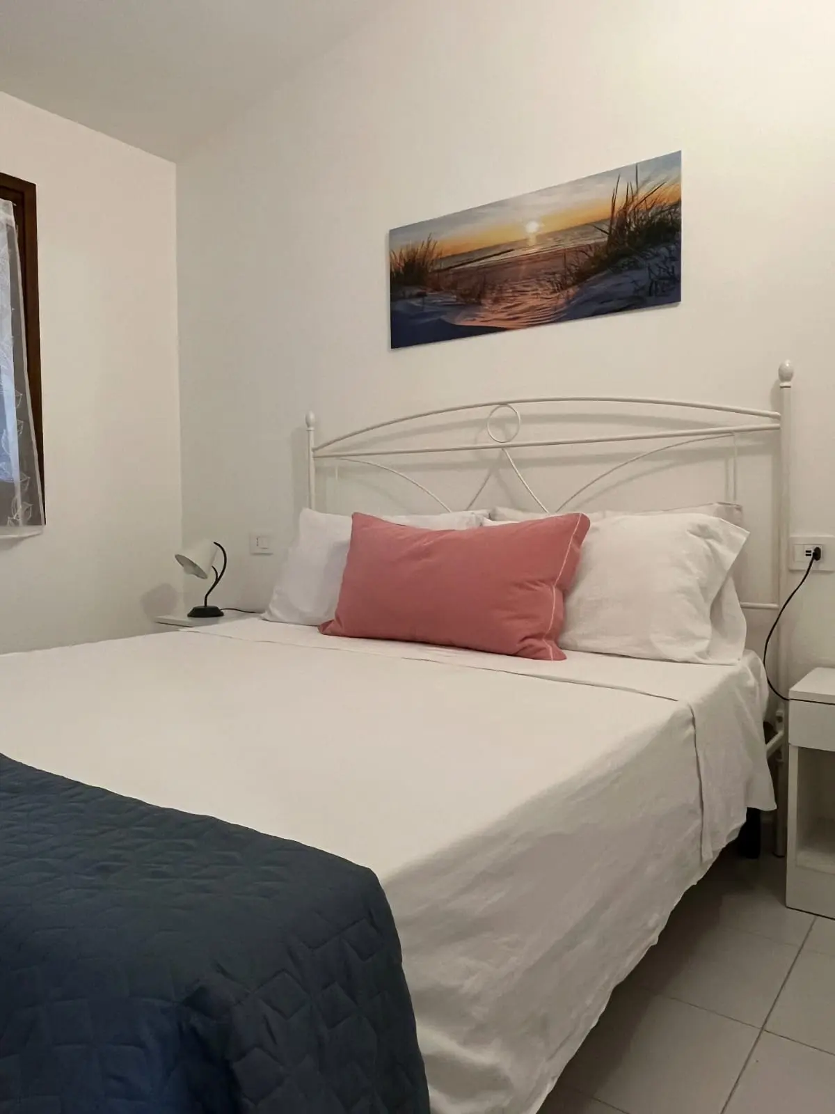 Queen-size bed with crisp linen and Sardinian sunset artwork