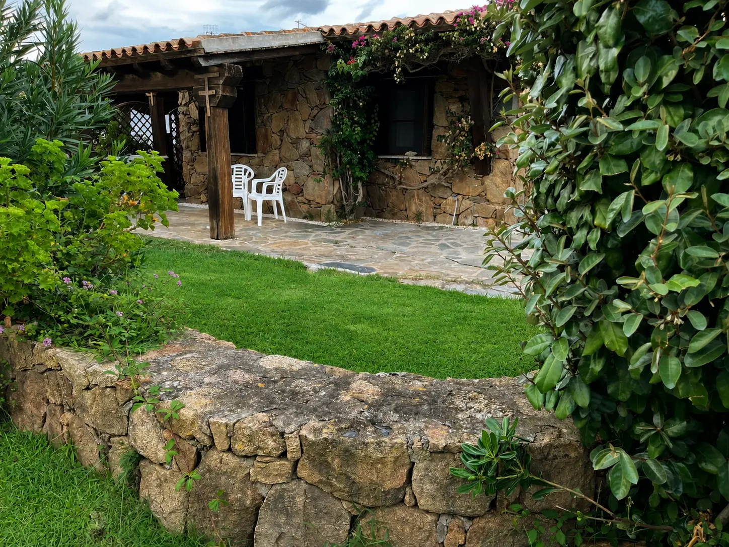 Shaded porch, dry-stone wall and flowering Mediterranean garden