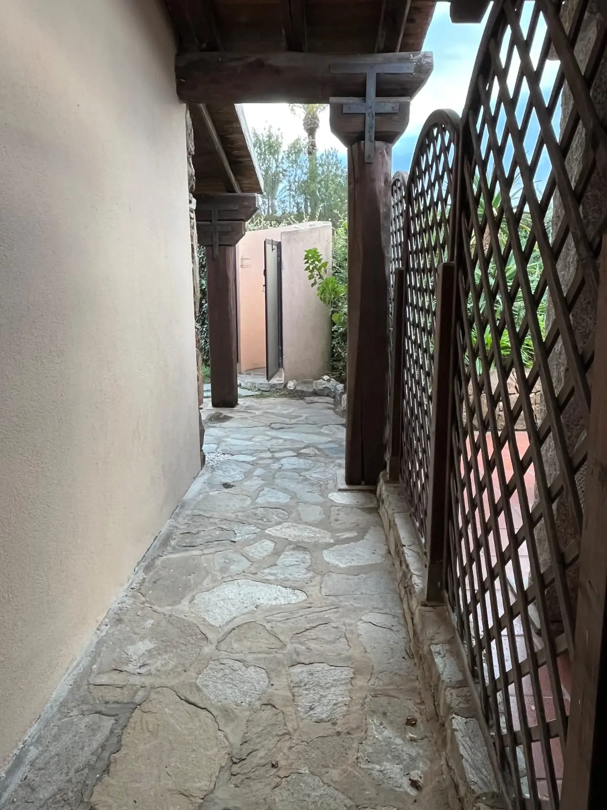 Stone-paved side entrance under a dark timber pergola