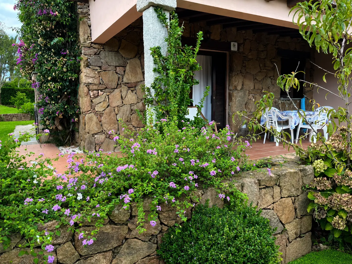 Sardinian stone facade, flowering garden and covered dining veranda