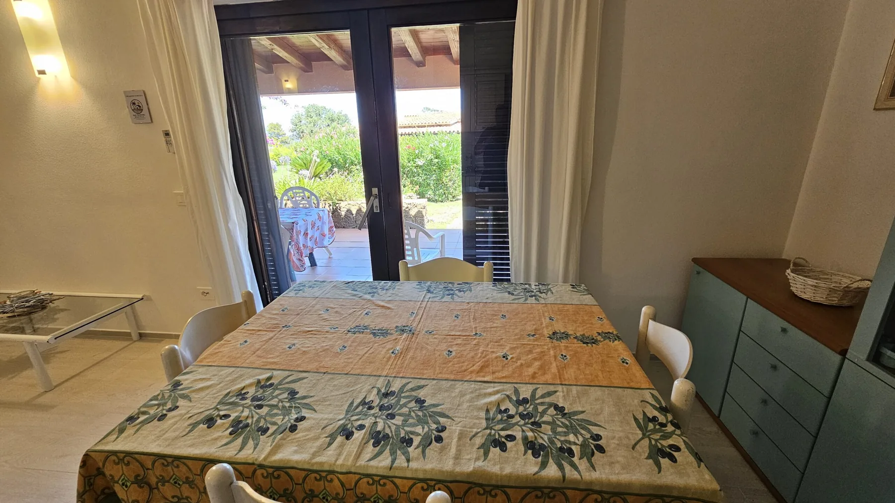 Indoor dining table with the patio doors open to the outdoor table and garden