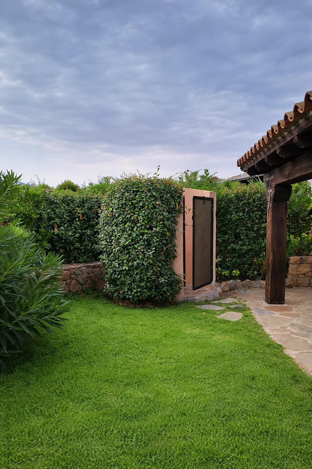 Outdoor shower tucked into the hedge at the edge of the lawn
