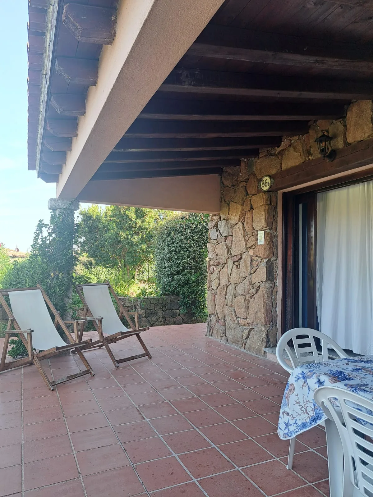 Covered patio under timber beams with two deckchairs and the outdoor dining table
